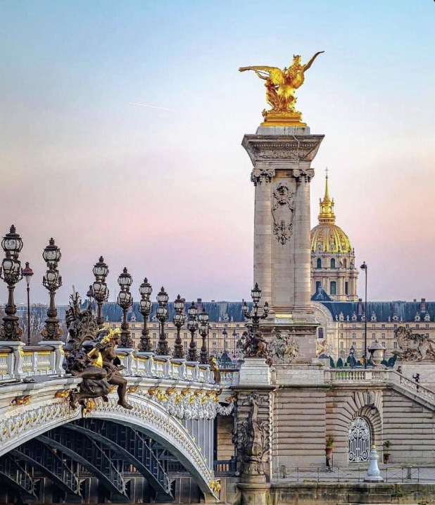 Pont Alexandre III bridge in Paris showing ornate lamps, golden hour reflections on the Seine River